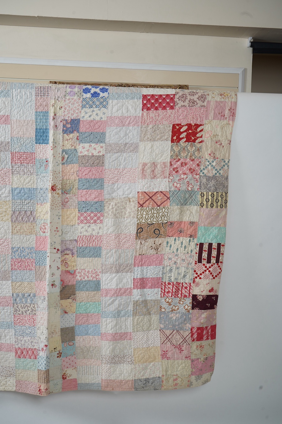 A late 19th early 20th century English cotton ‘scrap bag’ quilt., Made from a large variety of fashionable printed floral, striped and checked cottons of the day, cut into different sized rectangles and squares. Backed w